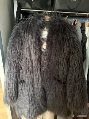 Odd molly grå pälsjacka - Säljer en helt ny Odd Molly mörkgrå långhårig pälsjacka med oversized passform och snyggt blommigt och paisleymönstrat innerfoder. Perfekt nu inför hösten och vintern. Den är i storlek 4 vilket motsvarar XL 44/46