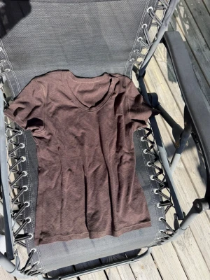 Brun v-ringad t-shirt - En enkel brun t-shirt med v-ringning och korta ärmar. Tillverkad i mjukt bomullsmaterial som känns skönt mot huden. Perfekt till jeans eller shorts för en avslappnad look.