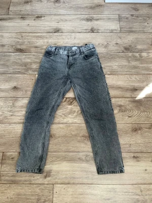 Grå jeans från grunt - Ett par grå tvättade jeans med rak passform. De är storlek 150 och är lite slitna bak på ena benet.