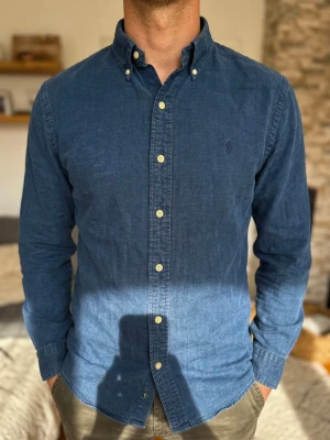 Mörkblå skjorta från Polo Ralph Lauren (Slim Fit) oxford - Snygg blå skjorta med button-down krage och vita knappar. Skjortan har lång ärm och en liten broderad logga på bröstet. Tillverkad i mjuk bomull som känns skön mot huden. Perfekt till jeans eller chinos för en clean look. Storlek S. Snabb Leverans!