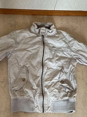 Beige jacka - Jag säljer en jacka i storlek M från ett välkänt märke! Jackan är i mycket bra skick och säljs för 150 kr. Perfekt för dig som vill ha kvalitet och stil.  Är du intresserad eller har frågor? Tveka inte att kontakta mig!
