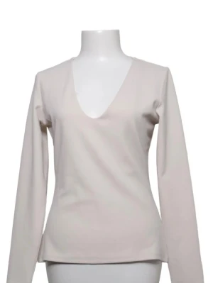 Beige långärmad v-ringad topp - Stilren beige topp med lång ärm och djup v-ringning. Enkel och clean design som passar till många olika looks. Tillverkad i ett mjukt material som känns skönt mot huden.