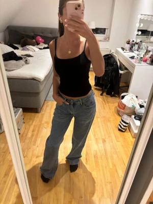 Blåa raka jeans med hög midja - Säljer ett par ljusblå jeans med rak passform och hög midja. Jeansen har klassisk femficksdesign och är tillverkade i ett mjukt denimtyg. Perfekta för en avslappnad och trendig look.