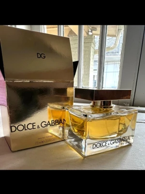 Dolce & Gabbana The One EdP 75ml - Lyxig parfym från Dolce & Gabbana, The One Eau de Parfum i 75 ml flaska. Flaskan är genomskinlig med guldigt lock och parfymen har en gyllene färg. Kommer i en elegant, spegelblank guldig kartong. Perfekt för dig som gillar exklusiva dofter.