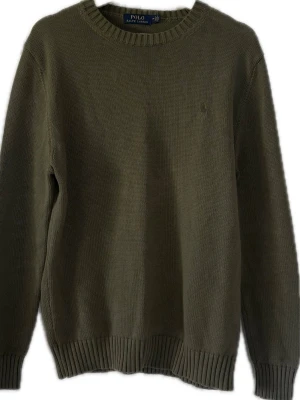 Olivgrön stickad tröja Polo Ralph Lauren - Olivgrön stickad tröja från Polo Ralph Lauren med rund halsringning och diskret broderad logga på bröstet. Tröjan har långa ärmar och ribbade muddar vid ärmslut och nederkant. Perfekt för lager på lager och enkel att matcha. ‼️ALDRIG ANVÄND‼️
