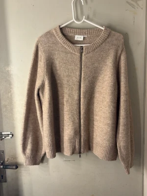  zip-kofta  - Mysig beige kofta från Vila med dragkedja framtill. Koftan har rund halsringning, ribbade muddar vid ärmslut och nederkant samt en mjuk, stickad känsla. Perfekt för lager på lager och enkel att matcha med olika outfits. Perfekt höstplagg!🍂🍁