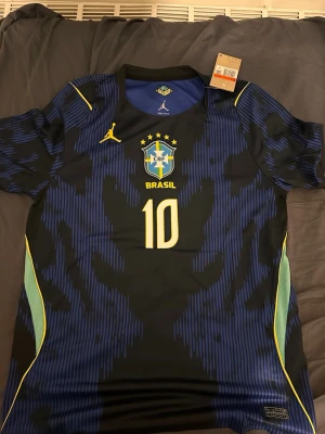 Blå Brasilien fotbollströja neymar Vm 2026  - Snygg blå och svart Brasilien fotbollströja med nummer 10 och gula detaljer. Tröjan har CBF-logga, rund hals och korta ärmar. Tillverkad i lätt och ventilerande material, perfekt för fotbollsträning eller match.