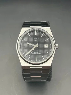 Tissot PRX Powermatic 80 klocka - Säljer en stilren Tissot PRX Powermatic 80 klocka i silver med svart urtavla och datumvisning. Klockan har ett klassiskt armband i rostfritt stål och en elegant, fyrkantig boett. Perfekt för dig som gillar tidlös design och schweizisk precision. 