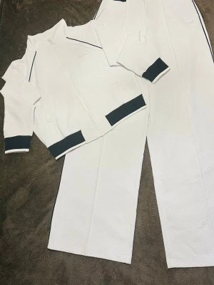 GUESS set – Full-Zip Sweatshirt & Flare-Leg Sweatpants 🤍 - Superfint och elegant set från GUESS i vitt med svarta detaljer. 🤍🖤  Setet består av jacka med dragkedja och flare-byxor. Endast använt en gång, så det är i mycket fint skick, nästan som nytt.  Nypris för hela setet var 1 610 kr och orderbekräftelse finns. Säljs som komplett set. ✨