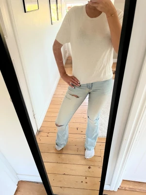 Vit basic t-shirt i bomull - En enkel vit t-shirt med rund hals och korta ärmar. Tillverkad i mjuk bomull och har en klassisk, normal passform. Perfekt att matcha med jeans eller kjol för en clean och stilren look.