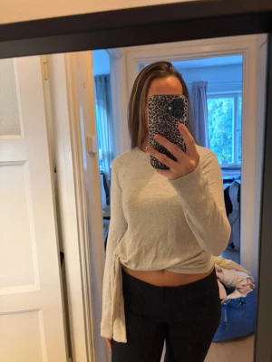 Ljusbeige långärmad tröja - En enkel och stilren ljusbeige långärmad tröja i mjukt material. Tröjan har rund halsringning och en något lös passform som ger en avslappnad look. Perfekt att matcha med jeans eller leggings för en clean och modern stil.