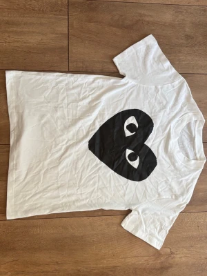 CDG Play T-shirt i vitt med svart hjärta 🤍🖤 (Strl S) - Säljer en skitsnygg och klassisk vit t-shirt från Comme des Garçons PLAY med det stora svarta ögon-hjärtat i storlek S. Använd sparsamt och i jättefint skick! Inget kvitto finns, men kika gärna på bilderna. Skriv ett DM om du vill ha mått eller funderar över något! ✨ 