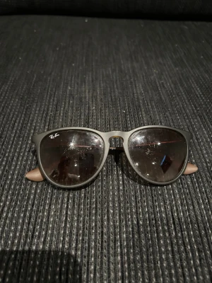 Ray-Ban solglasögon - Klassiska svarta solglasögon från Ray-Ban med rundade bågar och mörka glas. Snygg och tidlös design med bruna skalmar som ger en schysst kontrast. Perfekta för soliga dagar och passar till de flesta outfits.
