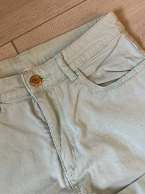 Ljusbeige bomullsshorts - Säljer ett par ljusbeige shorts i bomull med klassisk femficksdesign och gylf med knapp. Shortsen har bälteshällor och en enkel, stilren look som passar perfekt till sommaren.