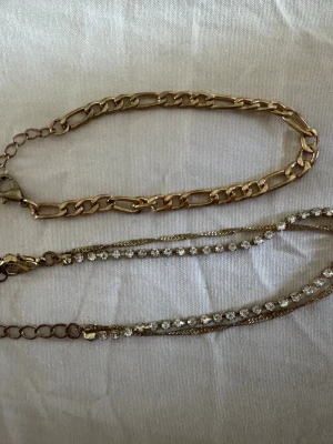 Två guldiga armband med kedja och stenar - Säljer två snygga armband i guldfärg. Det ena har en chunky kedjelänk i olika storlek, och det andra är tunnare med små glittrande stenar & en tunn kedja!😍Perfekta för att mixa och matcha till olika outfits. Passar dig som gillar stilrena men ändå vackra och staplepiece smycken som passar till alla tillfällen!🩷De är använda några gånger men utan fel. Osäker på märket! Hör av vid frågor eller bud, rabbat på bundles❤️Mer smycken på min profil🤍