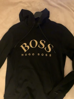 Hugo Boss mjukisset  - Säljer detta snygga och bekväma Hugo Boss-set i svart💕Perfekt för både vardag, skolan eller en mysig hemmadag💌Använt men fortfarande i fint skick utan större anmärkningar🪷   Storlek: M på både hoodie & mjukisbyxorna  Fickdetaljer: finns en fick framme på hoodien och även små fickor vid sidan av byxorna   Skriv till mig ifall du har frågor, vill ha fler bilder eller vill diskutera pris!!🪷💕
