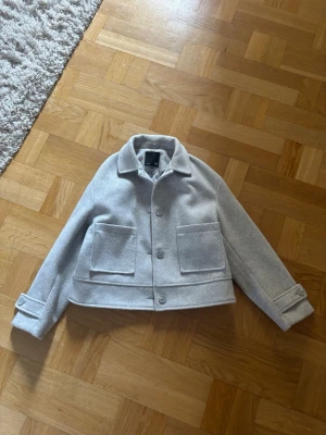 Ljusgrå cropped jacka med fickor - Jag säljer min jacka eftersom att den tyvärr är förstor för mig. Använt den fåtal gånger. Skriv för fler bilder eller om det finns frågor.