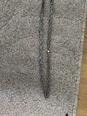 Kedjehalsband i silverfärg - Snyggt halsband med robust kedjedesign i silverfärgad metall. Länkarna är rektangulära och ger ett stilrent och modernt intryck. Perfekt för dig som gillar minimalistiska accessoarer med lite edge. Den har lite rost på några ställen men syns inte jätte mycket