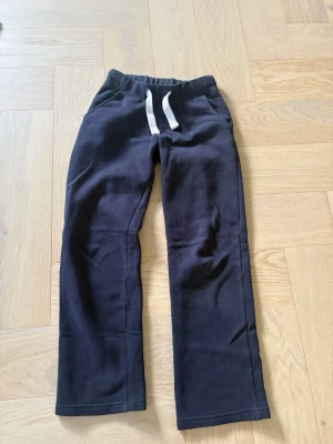  Mjukisbyxor från Russemerch - Säljer ett par marinblå mjukisbyxor med vita dragsnören i midjan från russemerch. Byxorna har raka ben och resår i midjan för skön passform. Perfekta för chill eller träning. Materialet känns mjukt och bekvämt.