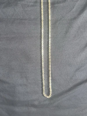 Guldfärgat kedjehalsband i silver - Snyggt halsband i guldfärgat silver med en unik kedjedesign. Halsbandet har ett klassiskt karbinlås och är tillverkat i 925 sterling silver. Perfekt för att lyfta din outfit med en stilren detalj.