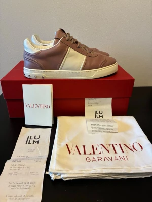 Valentino Garavani sneakers rosa/vit - Snygga sneakers från Valentino Garavani i en kombination av ljusrosa och vitt läder. Skorna har klassisk låg profil, vita sulor och silverfärgade nitar på hälen. Perfekta för dig som vill ha en exklusiv och trendig look.