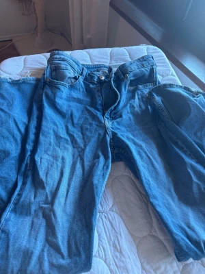 Blåa jeans highwaist bootcut - Säljer ett par ljusblå jeans med hög midja och bootcut. Används mycket men väl omhändertaget. Enbart slitage vid fötterna då jag är kort.