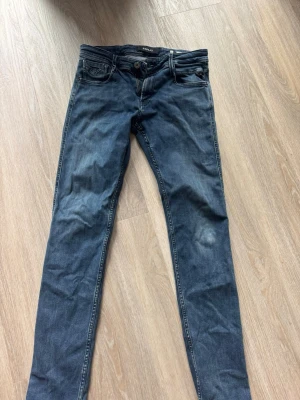 Mörkblå skinny jeans från Replay - Snygga mörkblå skinny jeans från Replay med klassisk femficksmodell och låg midja. Jeansen har diskreta slitningar och kontrastsömmar som ger en cool look. Perfekta till sneakers eller boots för en avslappnad stil.