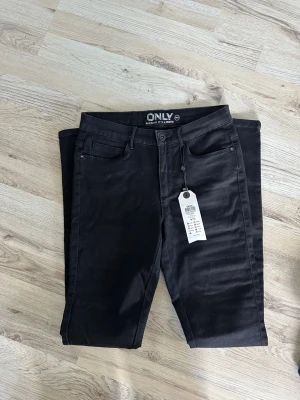 Svarta skinny jeans från ONLY - Snygga svarta skinny jeans från ONLY med klassisk femficksdesign och hög midja. Jeansen har stretchigt material för en bekväm passform och smala ben. Perfekta att matcha med en hoodie eller t-shirt.