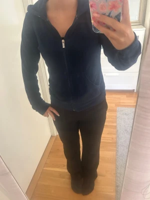 Mörkblå hoodie med dragkedja - Mysig mörkblå hoodie i mjukt tyg med dragkedja framtill och huva. Modellen har långa ärmar och två fickor på sidorna. Perfekt för en avslappnad och chill stil.