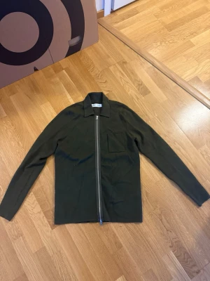 Samsøe Samsøe zip - Nypris 2400kr, inte mycket använd. Passar nog både S och M då den är ganska lång i ärmar. Stilren mörkgrön overshirt från Samsøe Samsøe med rak passform, dragkedja framtill och klassisk krage. En bröstficka på vänster sida. Perfekt lager-på-lager-plagg i mjukt material.