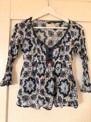 Mönstrad blå och vit blus💙🤍 - Säljer min fina odd molly blus med blått och vitt mönster, v-ringning och dekorativ spetsdetalj framtill. Tillverkad i ett tunt, luftigt material som ger en avslappnad look. Kom gärna med egna bud!