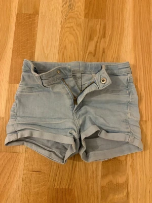 Ljusblå jeansshorts  - Säljer ett par ljusblå shorts i gott skick som passar barn. Står inte vart de är ifrån. På lappen står det 6-7 år men de passade mig när jag var 10 så det beror på. Skriv för mått. Pris kan diskuteras. :)