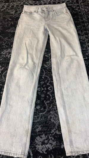 Ljusgrå raka jeans - Säljer ett par ljusgrå jeans med rak passform. Jeansen har en fransad detalj på bakfickorna.
