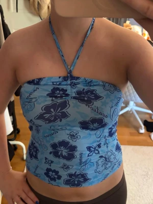 Blå blommig halterneck tubtopp - Säljer en blå tubtopp med halterneck och blommigt mönster i olika blå nyanser. Toppen är ärmlös och har en bandeau-form med smala band som knyts i nacken. Perfekt för sommarens alla tillfällen! Står ej storlek men mellan XS och S! Skriv pm vid funderingar!☺️