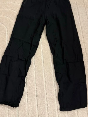 Svarta loose byxor med rak passform - Säljer ett par svarta byxor med loose fit och rak passform. Byxorna har enkel design utan synliga detaljer och är perfekta för en avslappnad stil. Tillverkade i ett mjukt material som känns skönt mot huden.
