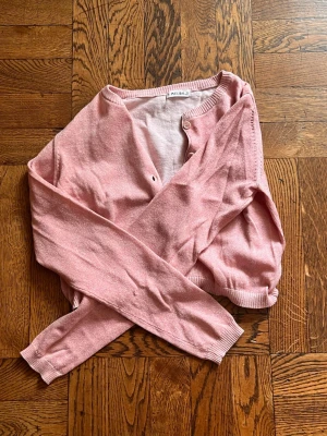 Ljusrosa cardigan från Melby - Söt ljusrosa cardigan från Melby med rund halsringning och knappar framtill.🤍 Tröjan har långa ärmar och glittriga detaljer! passar perfekt för att slänga över en topp eller skjorta❣️❣️🥹