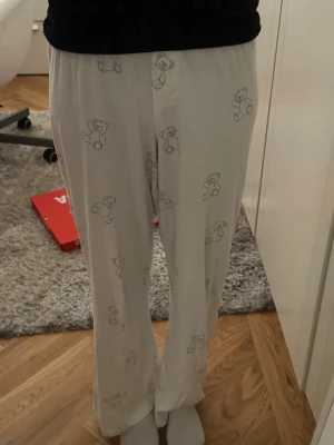 Pyjamasbyxor - Säljer ett par vita pyjamasbyxor från Brandy Melville med sött nallemönster. Byxorna har rak passform och resår i midjan. One size. Passar mig som är 164 cm bra.