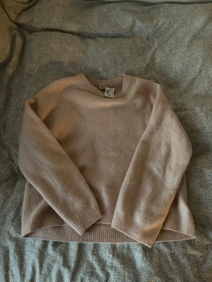 Ljusrosa stickad tröja - Mysig ljusrosa stickad tröja med rund halsringning och ribbade muddar vid ärmslut och nederkant. Tröjan har en avslappnad passform och är perfekt för kyliga dagar. 🩷