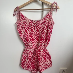 Rosa mönstrad playsuit - Superfin mörkrosa och vit mönstrad playsuit från Crocker och ger en snygg passform med justerbara snören. Perfekt för en varm sommar då den är luftig🥰