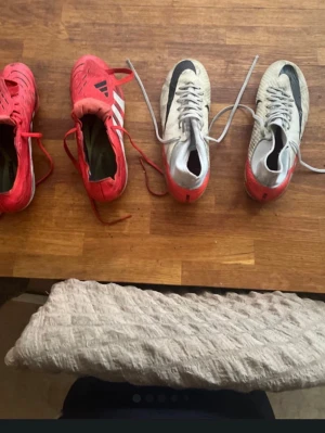 Två par fotbollsskor röd/vit - Säljer två par fotbollsskor, ett par i rött och vitt med klassiska ränder och ett par i vitt, rött och svart med stor swoosh. Båda paren har dobbar för gräsplan och snörning. Perfekta för dig som vill ha snygga och funktionella skor på planen. Dem röda skorna är stl 43 och den vita 42! Den röda är för 370kr och den vita 400 Och 750kr för båda!