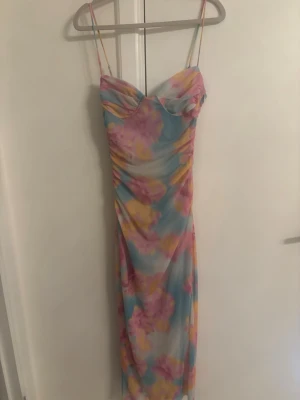 Ny pastellfärgad Zara klänning - Säljer en långklänning med tunna axelband och blommigt mönster i pastellfärger som blått, rosa och gult. Klänningen har en figurnära passform och lätt rynkade detaljer framtill. Perfekt för sommarens alla tillfällen!
