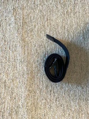Mörkblått flätat bälte Jack & Jones - Snyggt mörkblått flätat bälte från Jack & Jones med klassiskt metallspänne och detaljer i skinn. Perfekt accessoar för att lyfta din outfit och funkar till både jeans och chinos.