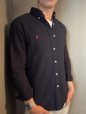 Ralph Lauren skjorta marinblå – M slim fit - Säljer denna stilrena och snygga marinblå Ralph Lauren skjorta. Skjortan är i mycket bra skick och storlek M slim fit. Perfekt för både vardag och mer uppklädda tillfällen. Har du några frågor? Tveka inte att höra av dig. Allt gott från Deluxe Garderoben ⭐️