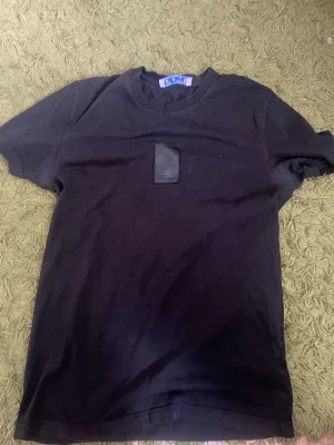 Svart Off-White t-shirt med patch - Säljer en svart t-shirt från Off-White med en stor svart patch med logga på bröstet. Klassisk rund hals och korta ärmar. Tillverkad i mjuk bomull för skön passform. Perfekt för dig som gillar streetwear och stilrena plagg.