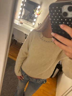 Beige stickad tröja med silvrig detalj🩶 - Säljer en beige stickad tröja med rund hals och dekorativa pärlor längs halsringningen. Tröjan har lång ärm och är gjord i ett mjukt, fluffigt material som känns riktigt mysigt. Perfekt för dig som gillar en enkel men ändå lite extra look.Original pris: 299kr💞💞