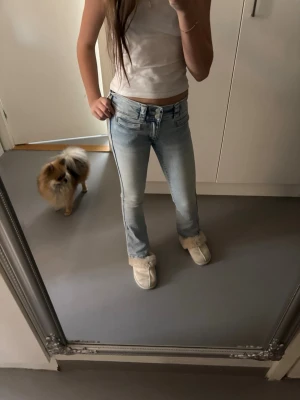 Bootcut jeans med låg midja H&M - Säljer ett par ljusblå bootcut jeans från H&M med låg midja och justerbar midja. Jeansen har klassisk femficksmodell och snygg tvättad look. Perfekta för dig som gillar en avslappnad men trendig stil.
