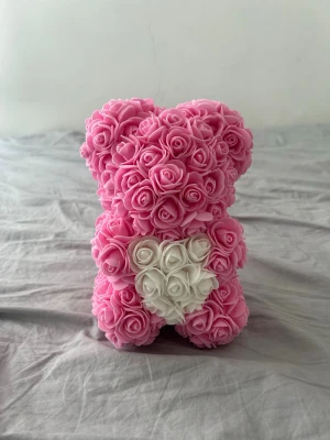 Nallebjörn av rosor i rosa och vitt - Söt dekorationsnalle formad av små konstgjorda rosor i rosa med ett hjärta av vita rosor på magen. Perfekt som present eller inredningsdetalj. Tillverkad av mjukt skumplastmaterial och har en unik, romantisk look.
