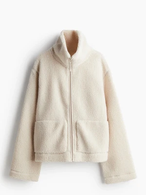 teddyjacka  - Mysig teddyjacka i krämvit färg med hög krage och hel dragkedja framtill. Jackan har två stora fickor framtill och är tillverkad i fluffigt teddy-material som ger en avslappnad och trendig look.