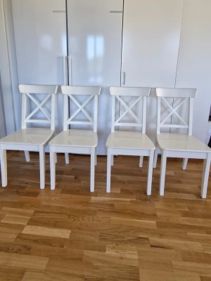 Ikea Fyra vita trästolar  - Säljer fyra stilrena vita stolar i trä med klassisk kryssrygg. Stolarna har raka ben och en enkel, modern design som passar till de flesta matbord. Perfekta för köket eller matsalen om du vill ha en ljus och fräsch känsla.