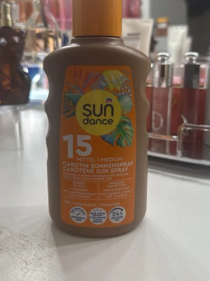 Sundance Carotene Solspray SPF 15 - Säljer en solspray från Sundance med SPF 15. Flaskan har tropiskt motiv och innehåller karotenextrakt och vitamin E för skydd och en fin sommarbränna. Sprayen är vattenresistent och ger omedelbart skydd mot UVA- och UVB-strålar.